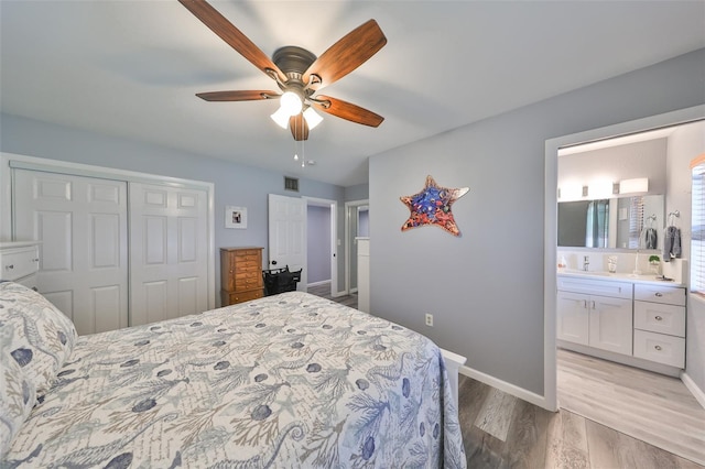 bedroom with ceiling fan, light wood-type flooring, a closet, ensuite bath, and sink