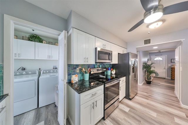 kitchen featuring appliances with stainless steel finishes, light hardwood / wood-style flooring, washing machine and clothes dryer, and white cabinets