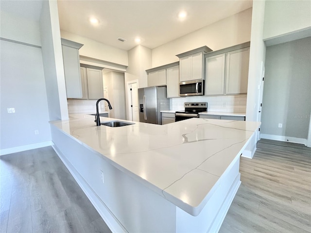 kitchen with sink, gray cabinets, kitchen peninsula, and appliances with stainless steel finishes