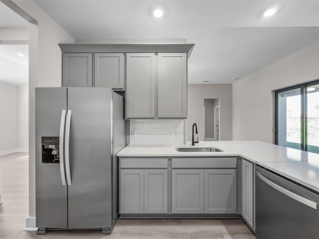 kitchen featuring light wood-type flooring, stainless steel appliances, sink, and gray cabinetry