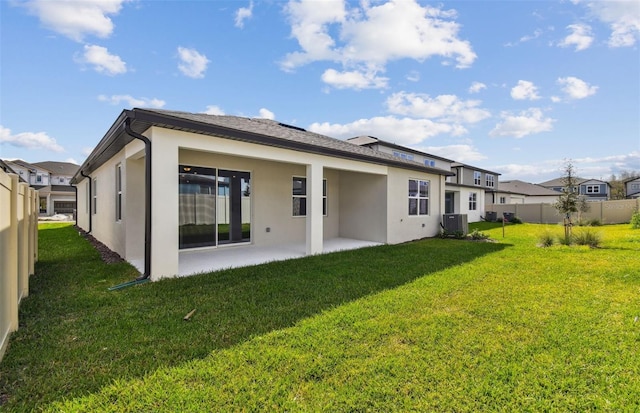 rear view of property with a yard, a patio, stucco siding, central AC, and fence