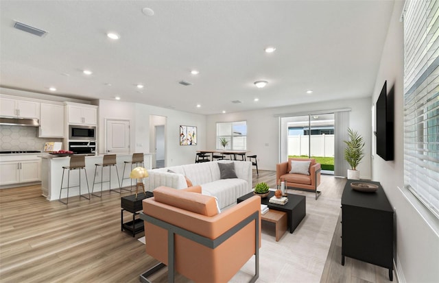 living area featuring light wood-style floors, baseboards, visible vents, and recessed lighting