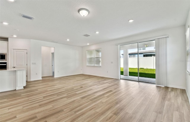 unfurnished living room featuring light wood-type flooring, visible vents, a textured ceiling, and recessed lighting