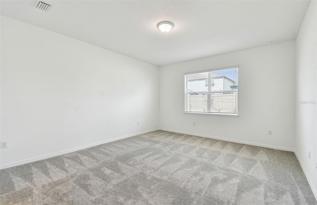 spare room with visible vents, light carpet, baseboards, and a textured ceiling