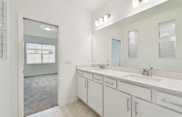 full bathroom featuring double vanity, baseboards, and a sink