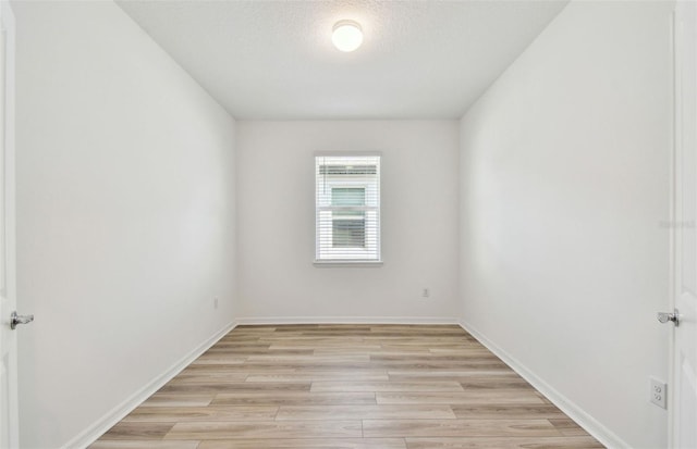 unfurnished room featuring a textured ceiling, light wood-style flooring, and baseboards