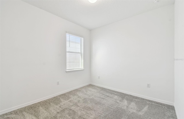 empty room featuring baseboards, a textured ceiling, and light colored carpet