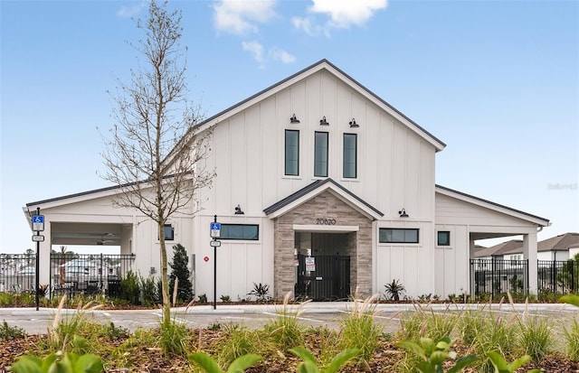 modern farmhouse with stone siding, board and batten siding, and fence