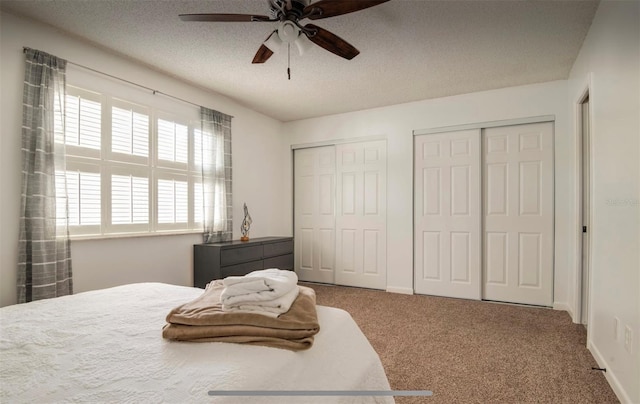 bedroom featuring two closets, ceiling fan, a textured ceiling, and carpet floors