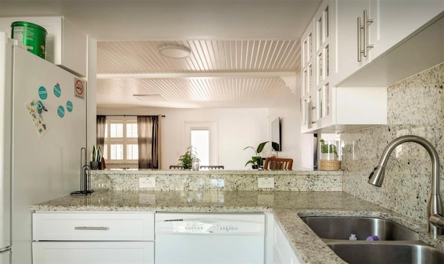 kitchen with light stone counters, sink, tasteful backsplash, white cabinetry, and white appliances