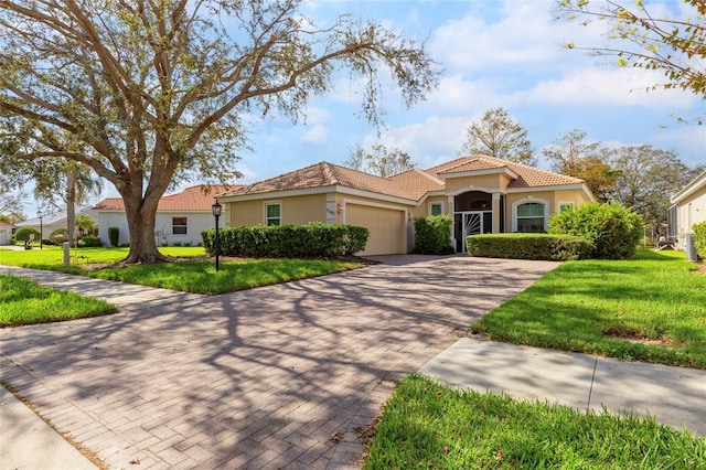 mediterranean / spanish-style home featuring a front yard, decorative driveway, an attached garage, and stucco siding