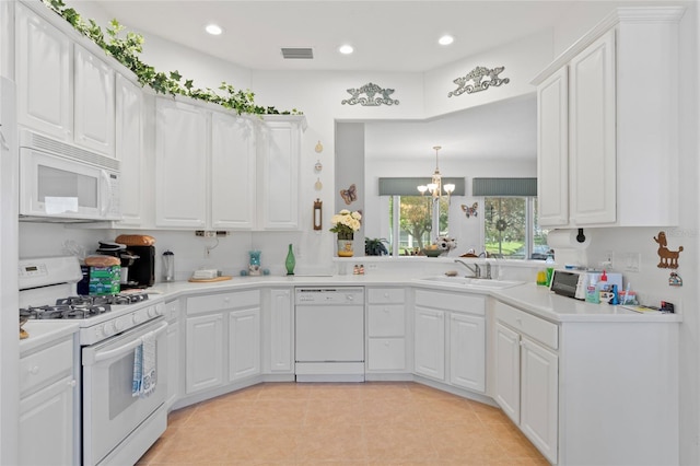 kitchen with white appliances, sink, hanging light fixtures, white cabinets, and an inviting chandelier