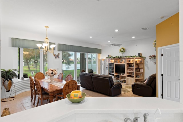 dining room with light tile patterned floors, plenty of natural light, and ceiling fan with notable chandelier