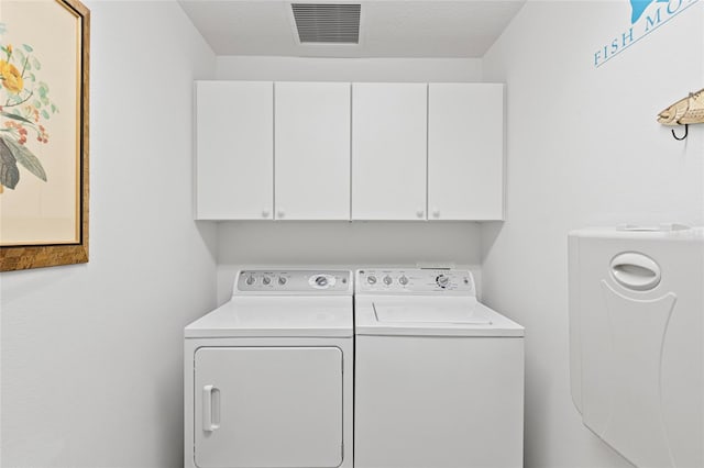 washroom featuring washer and clothes dryer, a textured ceiling, and cabinets