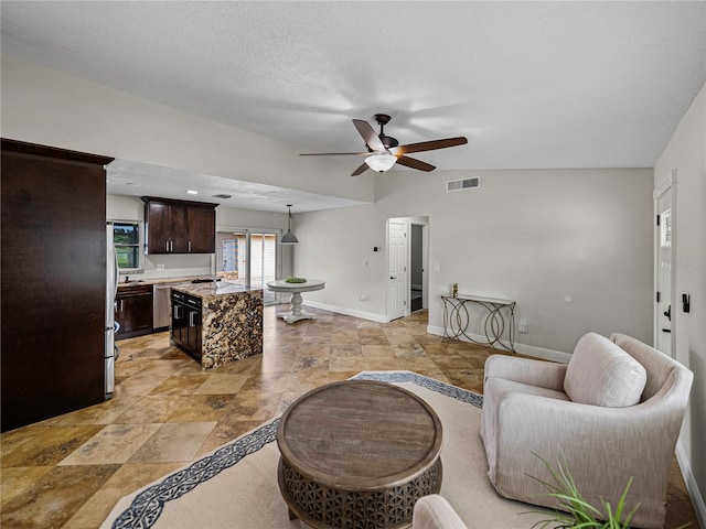 living room featuring ceiling fan, a textured ceiling, and lofted ceiling