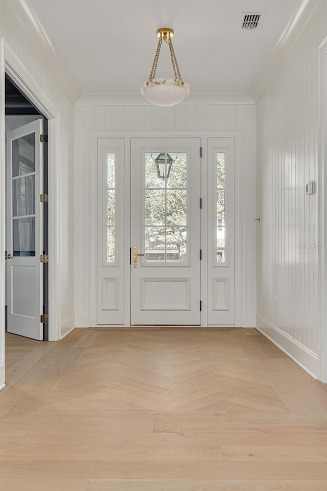 entryway with light parquet flooring and ornamental molding