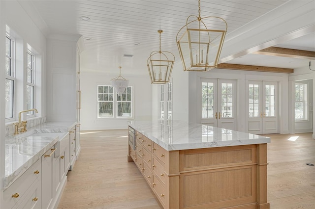 kitchen featuring sink, french doors, white cabinetry, a large island, and light hardwood / wood-style flooring