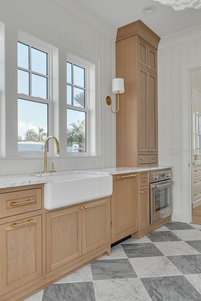 kitchen featuring a healthy amount of sunlight, stainless steel oven, and sink