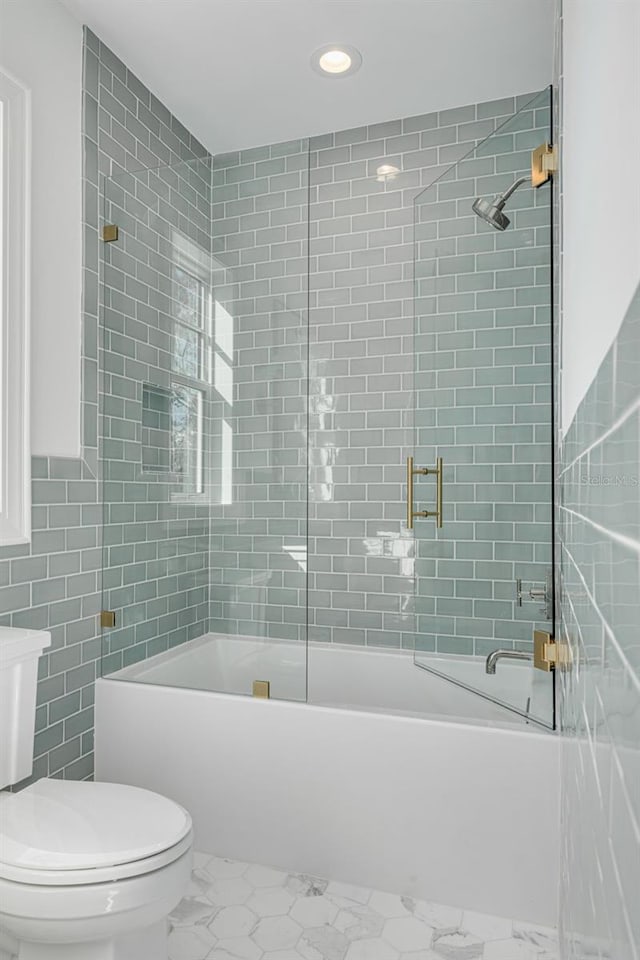 bathroom with toilet, combined bath / shower with glass door, and tile walls