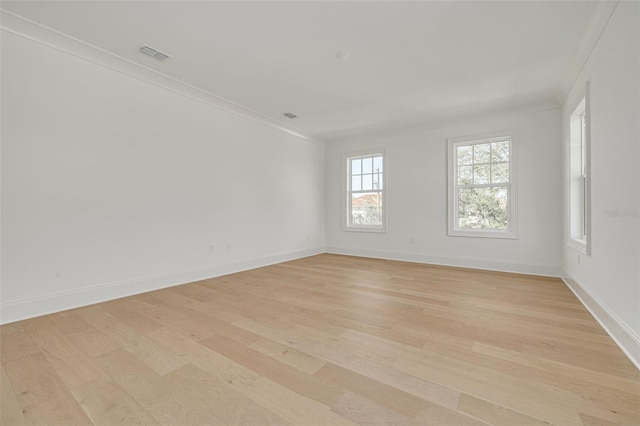 empty room with light hardwood / wood-style floors and crown molding