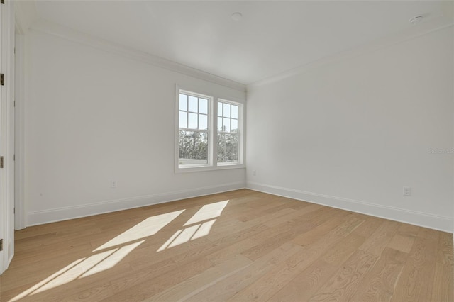 spare room with crown molding and light wood-type flooring