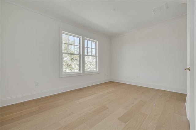 spare room with ornamental molding and light wood-type flooring