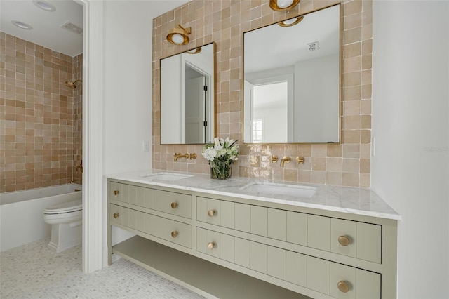 full bathroom with tile patterned floors, toilet, backsplash, tiled shower / bath combo, and vanity