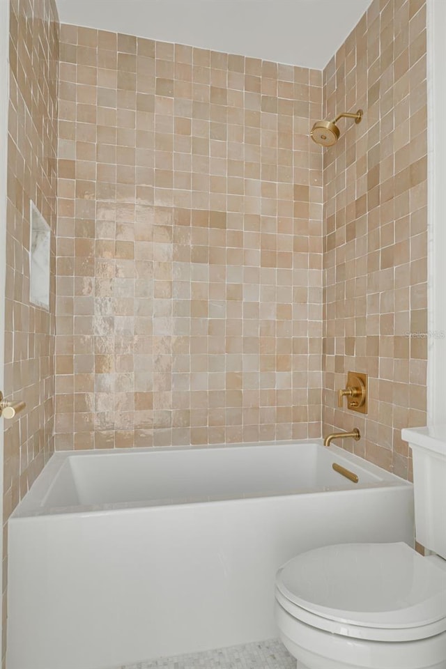 bathroom with tile patterned floors, tiled shower / bath combo, and toilet