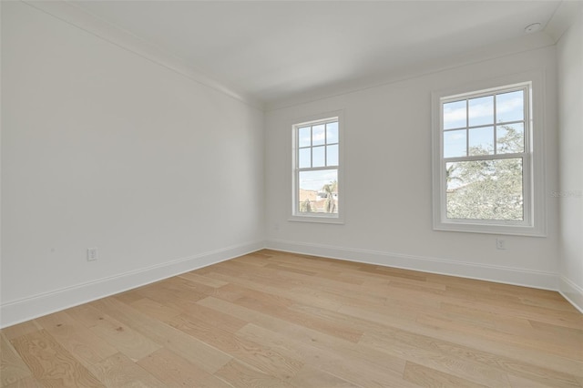 spare room featuring light hardwood / wood-style floors, crown molding, and plenty of natural light