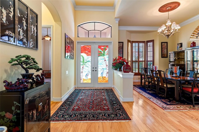 foyer entrance with ornamental molding, french doors, wood-type flooring, and plenty of natural light