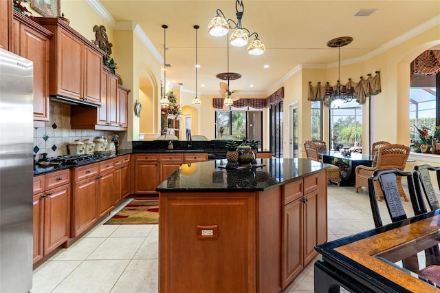 kitchen with crown molding, stainless steel refrigerator, pendant lighting, and ceiling fan with notable chandelier