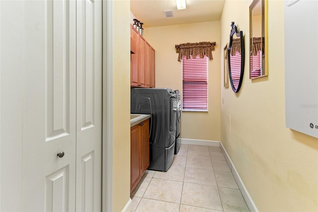 laundry room featuring washer and dryer, light tile patterned floors, and cabinets