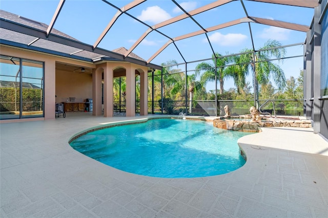 view of swimming pool with pool water feature, ceiling fan, a patio, and a lanai