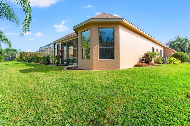 view of home's exterior featuring glass enclosure and a lawn