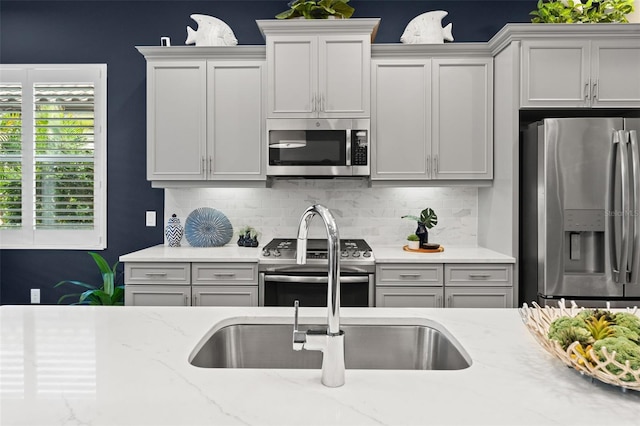 kitchen featuring light stone countertops, stainless steel appliances, and decorative backsplash