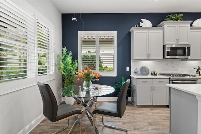 kitchen with appliances with stainless steel finishes, light hardwood / wood-style flooring, and tasteful backsplash