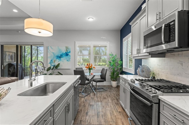 kitchen with appliances with stainless steel finishes, sink, pendant lighting, and a wealth of natural light