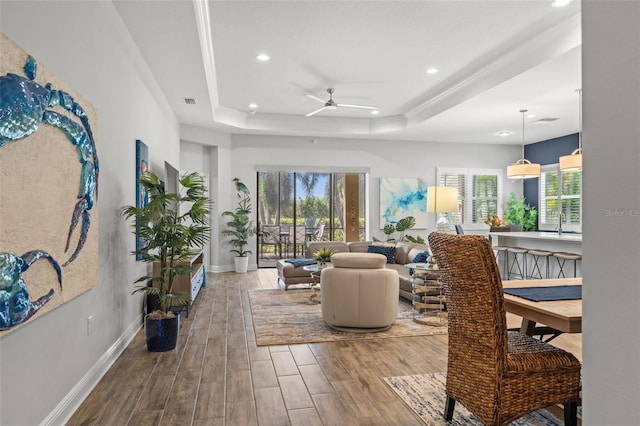 living room featuring ceiling fan, hardwood / wood-style flooring, and a raised ceiling