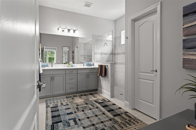 bathroom with vanity, tiled shower, and tile patterned flooring