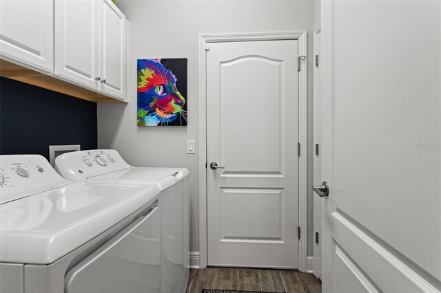 laundry room with dark wood-type flooring, washer and dryer, and cabinets