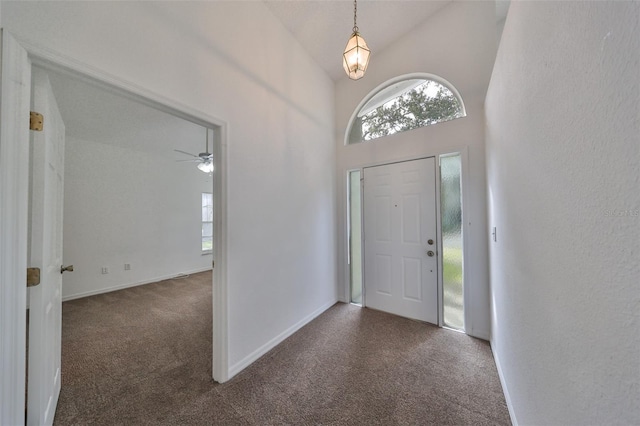 carpeted foyer entrance featuring ceiling fan and high vaulted ceiling