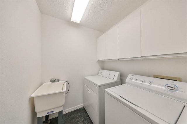 clothes washing area featuring separate washer and dryer, sink, cabinets, and a textured ceiling