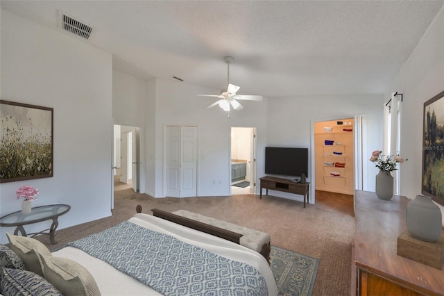 carpeted bedroom featuring ceiling fan, vaulted ceiling, a textured ceiling, and ensuite bath