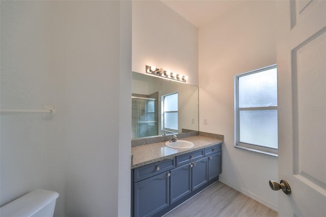 bathroom with hardwood / wood-style floors, vanity, toilet, and a shower with shower door