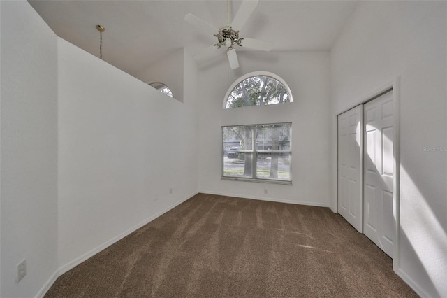 interior space with ceiling fan, high vaulted ceiling, and dark colored carpet