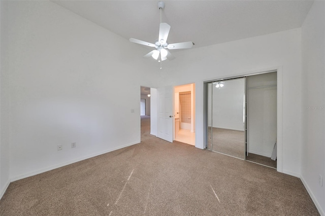 unfurnished bedroom featuring ceiling fan, carpet floors, high vaulted ceiling, and a closet