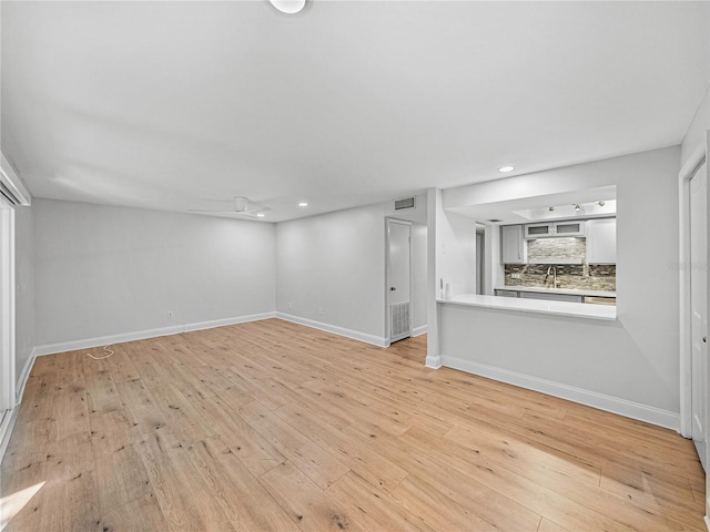 unfurnished living room with light hardwood / wood-style floors and sink