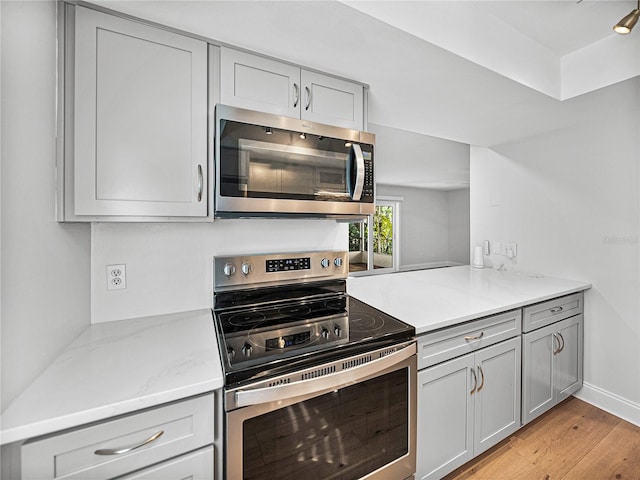 kitchen featuring gray cabinetry, appliances with stainless steel finishes, and light hardwood / wood-style flooring