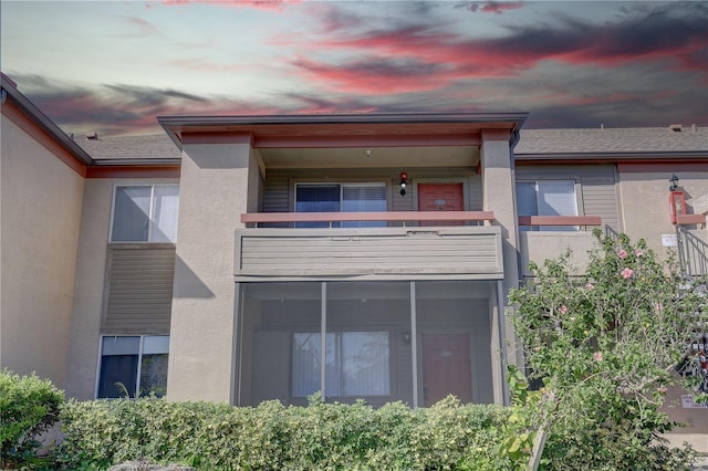 back house at dusk featuring a balcony