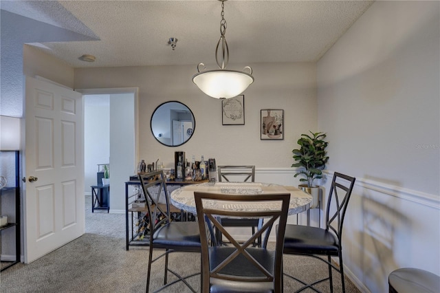 dining space featuring light carpet and a textured ceiling